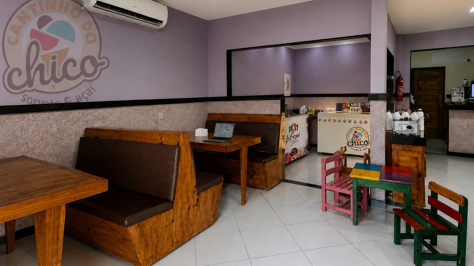 Ambiente interno da loja Cantinho do Chico, com mesas, sofás e cantinho infantil